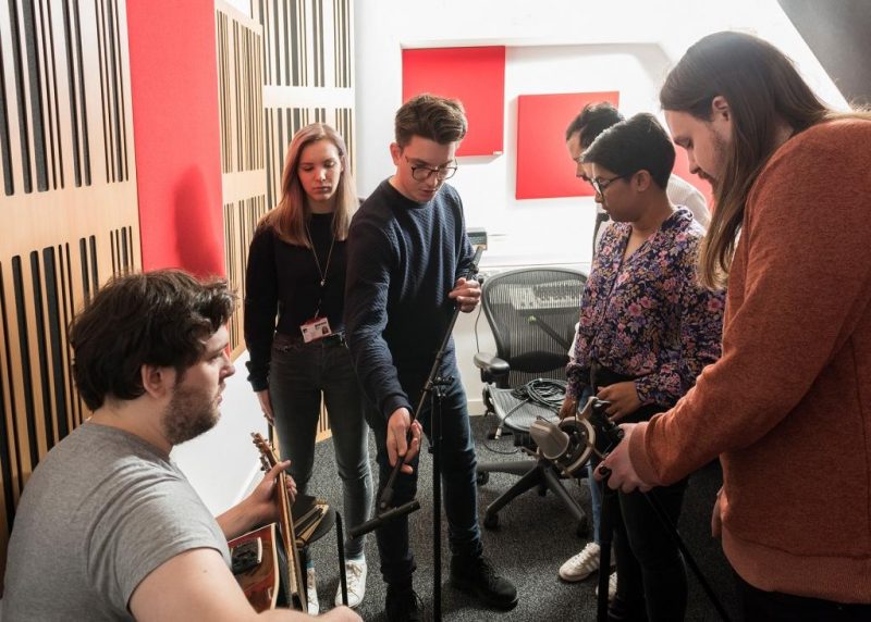 Abbey Road Institute teaching space incorporates GIK Acoustics Alpha Series and 242 Acoustic Panels in studio where students are adjusting microphone placement around guitarist